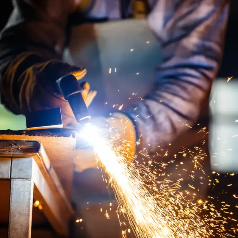 Profissional soldando uma peça de metal, com faíscas